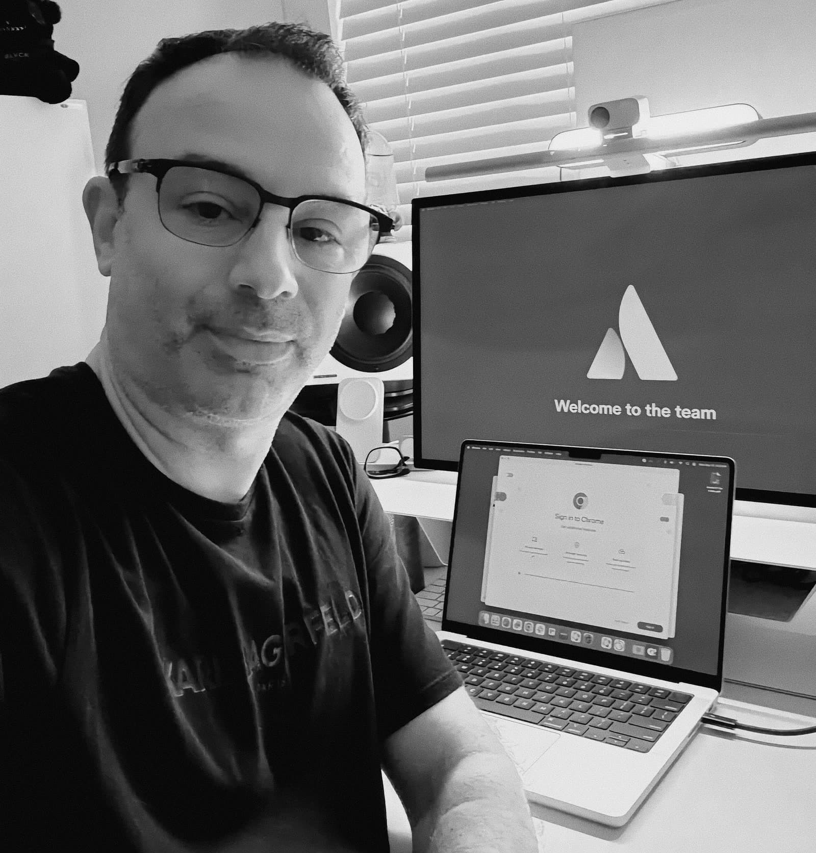Shane beside an Atlassian welcome message on a monitor.